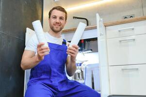 Klempner installiert oder Veränderung Wasser Filter. Ersatz aqua Filter. Handwerker Installation Wasser Filter Patronen im ein Küche. Installation von umkehren Osmose Wasser Reinigung System. foto