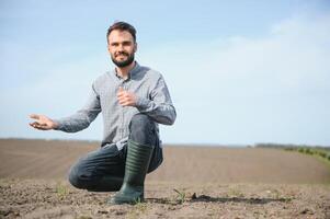 ein Farmer im Stiefel funktioniert im ein Feld gesät im Frühling. ein Agronom Spaziergänge das Erde, beurteilen ein gepflügt Feld im Herbst. Landwirtschaft. foto