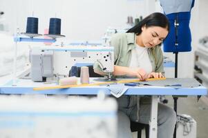 positiv jung Frau Nähen mit Fachmann Maschine beim Werkstatt. foto