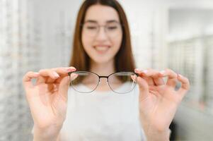 jung Frau mit Brille im optisch Geschäft - - schön Mädchen tragen Brille im Optiker Geschäft foto