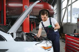 Porträt Schuss von ein gut aussehend Mechaniker Arbeiten auf ein Fahrzeug im ein Auto Service. modern sauber Werkstatt. foto