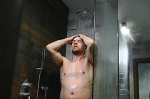 das Mann ist Waschen seine Haar, er verwenden Shampoo. foto