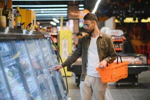 gut aussehend Mann Kauf etwas gesund Essen und trinken im modern Supermarkt oder Lebensmittelgeschäft speichern. Lebensstil und Konsumismus Konzept foto