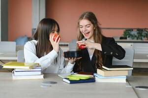 ein süß Mädchen lächelnd beim ihr Mitschüler während haben Mittagessen beim das Schreibtisch im Schule während ein brechen foto