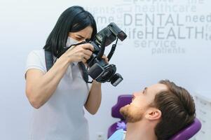 weiblich Zahnarzt Fotografien ihr Patienten Zähne im ein Dental Stuhl. foto