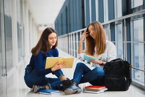 weiblich Studenten Sitzung auf das Fußboden und lesen Anmerkungen Vor Prüfung foto