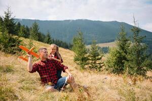 Familie von drei Menschen sich ausruhen im das Berge. Sie saß Nieder zu ausruhen, trinken Wasser nach ein schwer steigen zu das Berg. Sie sind müde aber glücklich. foto