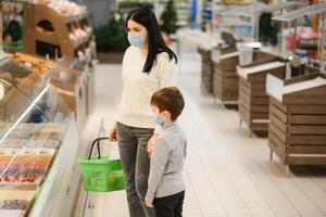 Porträt von ein Mutter und ihr wenig Sohn tragen schützend Gesicht Maske beim ein Supermarkt während das Coronavirus Epidemie oder Grippe Ausbruch. leeren Raum zum Text foto