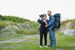 ein Paar von Touristen im Zeit von Ausflug Stahl und bewundern das schön Berg Landschaft. das Kerl Umarmungen das Mädchen. das Konzept von Liebe, Zärtlichkeit und Erholung foto