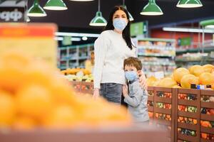 jung Frau und ihr Kind tragen schützend Gesicht Masken Geschäft ein Essen beim ein Supermarkt während das Coronavirus Epidemie oder Grippe Ausbruch. foto