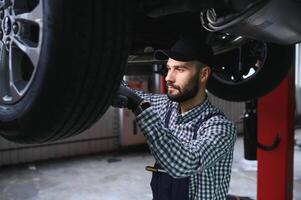 Auto Mechaniker Arbeiten unterhalb ein angehoben Auto foto