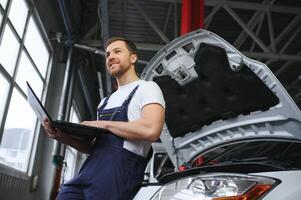 mit Laptop. Erwachsene Mann im Uniform funktioniert im das Automobil Salon. foto