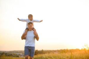 jung Vater wirft oben seine süß und wenig Sohn im das frisch Luft. Vaters Tag, Vater und seine Sohn Baby Junge spielen und umarmen draußen. foto