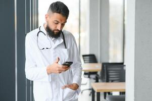 Porträt von ein jung arabisch Arzt Stehen im das das Klinik foto