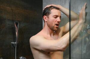 entspannend nach stressig Tag. Taille oben Porträt von nackt muskulös Gentleman nehmen Dusche beim heim. foto