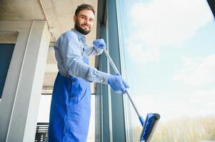 männlich Fachmann Reinigung Bedienung Arbeiter im Overall reinigt das Fenster und Geschäft Fenster von ein Geschäft mit Besondere Ausrüstung foto