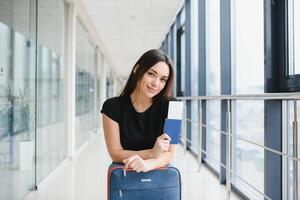 ziemlich Frau warten zum ihr Flug beim Flughafen foto