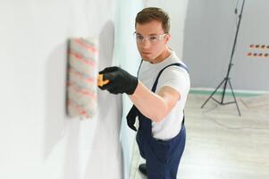 junge arbeiterin, die wand im zimmer malt foto