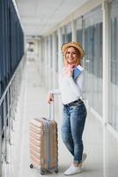 Mädchen Reisender Gehen mit Tragen halt Koffer im das Flughafen. Tourist Konzept. Frau Spaziergänge durch Flughafen Terminal mit Gepäck. Reise Konzept foto