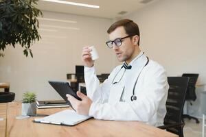 Arzt Arbeiten im seine Büro geben Beratungen online Über das Internet mit seine Laptop Computer. Telegesundheit foto