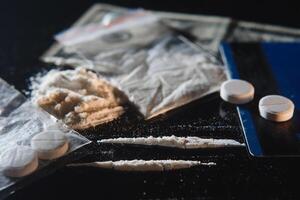 Kokain Droge Pulver Tasche und Stapel und Tabletten auf schwarz Hintergrund. foto