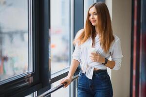 ziemlich Mädchen haben Kaffee durch das Fenster foto