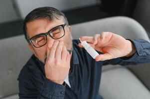 krank Mann mit Nasal- sprühen beim heim. foto