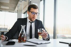 Alkoholismus beim arbeiten. müde Mitarbeiter Trinken Alkohol beim Arbeitsplatz, können nicht Griff betonen. foto