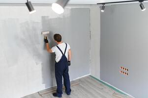 Arbeiter Maler Farben ein Mauer. Fachmann Baumeister macht Instandsetzung. foto