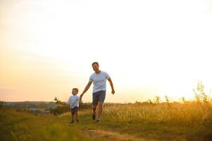 Vaters Tag. glücklich Familie Vater und Kleinkind Sohn spielen und Lachen auf Natur beim Sonnenuntergang foto