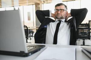 müde betont Büro Arbeiter Sitzung beim Schreibtisch und Denken, er ist Reiben seine Augen und Gefühl erschöpft. foto