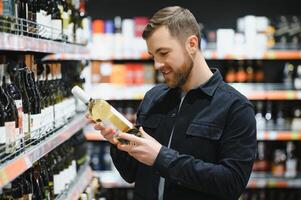 Mann im ein Supermarkt wählen ein Wein foto