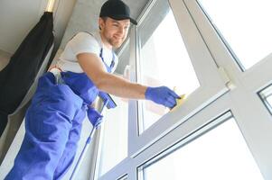 Heimwerker Reinigung das Fenster und lächelnd im ein Neu Haus foto