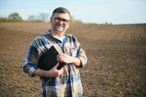 ein Farmer funktioniert im ein Feld gesät im Frühling. ein Agronom Spaziergänge das Erde, beurteilen ein gepflügt Feld im Herbst. Landwirtschaft. Clever Landwirtschaft Technologien. foto