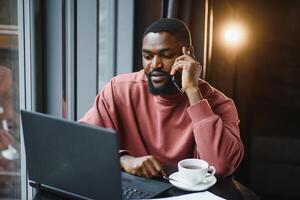 Geschäftsmann mit Telefon Arbeiten auf Laptop im Kaffee Geschäft. foto