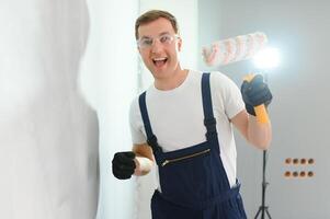 junge arbeiterin, die wand im zimmer malt foto