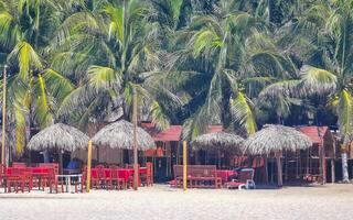 palmen sonnenschirme liegestühle strand wellen puerto escondido mexiko. foto