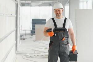 Porträt von positiv, gut aussehend männlich Baumeister im schwer Hut. r Handwerker im das Haus. foto