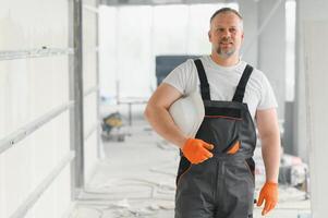 Porträt von positiv, gut aussehend männlich Baumeister im schwer Hut. r Handwerker im das Haus. foto