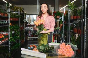 jung schön Frau Florist machen Strauß von Blumen beim Blume Geschäft foto