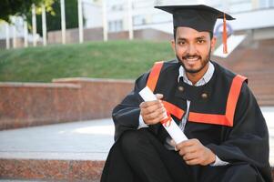 Porträt von erfolgreich indisch Schüler im Abschluss Kleid. foto