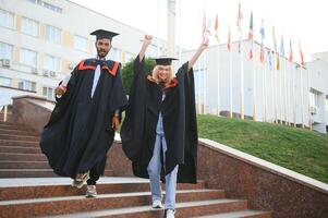 Ausbildung, Abschluss und Menschen Konzept - - glücklich International Studenten im Granatwerfer Bretter und Junggeselle Kleider. foto