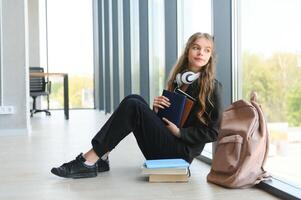 verärgert Teen Mädchen sitzen auf Fußboden traurig aussehen aus Fenster besorgt Über Teenager Problem beim Schule und Kommunikation mit Elternteil. besorgt Mädchen gespannt leiden Über Tyrannisieren beim Schule foto