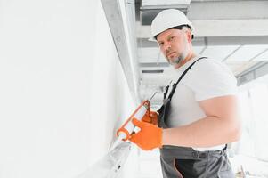 das Baumeister füllt das Nähte auf das Mauer mit versiegelt Silikon foto