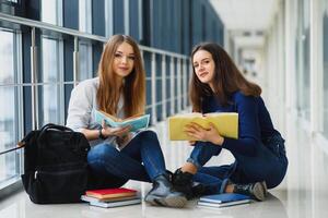 weiblich Studenten Sitzung auf das Fußboden und lesen Anmerkungen Vor Prüfung foto