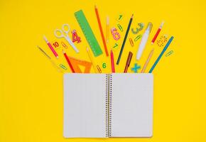 Schule Notizbuch und Schreibwaren Über Gelb Schreibtisch. zurück zu Schule abstrakt Hintergrund. Schule Ausrüstung. Vielfalt von Schule Lieferungen. eben legen foto