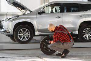 Mann reparieren ein Auto Rad im ein Garage foto
