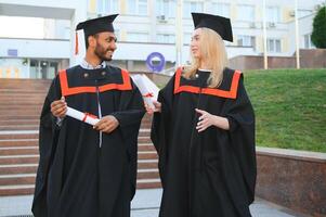 Ausbildung, Abschluss und Menschen Konzept - - glücklich International Studenten im Granatwerfer Bretter und Junggeselle Kleider. foto