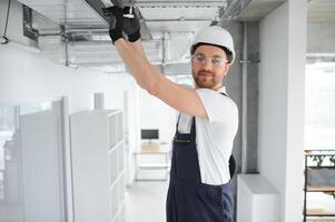 kaukasisch hvac Techniker Arbeiter im seine 40er Jahre testen neu Eingerichtet Warenhaus Belüftung System. kommerziell Heizung, Kühlung und Luft Belüftung Systeme foto