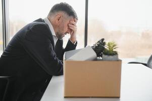 alt Mitarbeiter Verlassen Büro mit das Box voll von Besitz foto